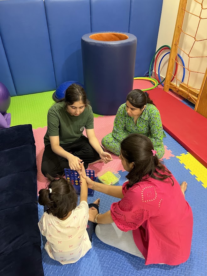 Children sitting on floor raising hands in classroom