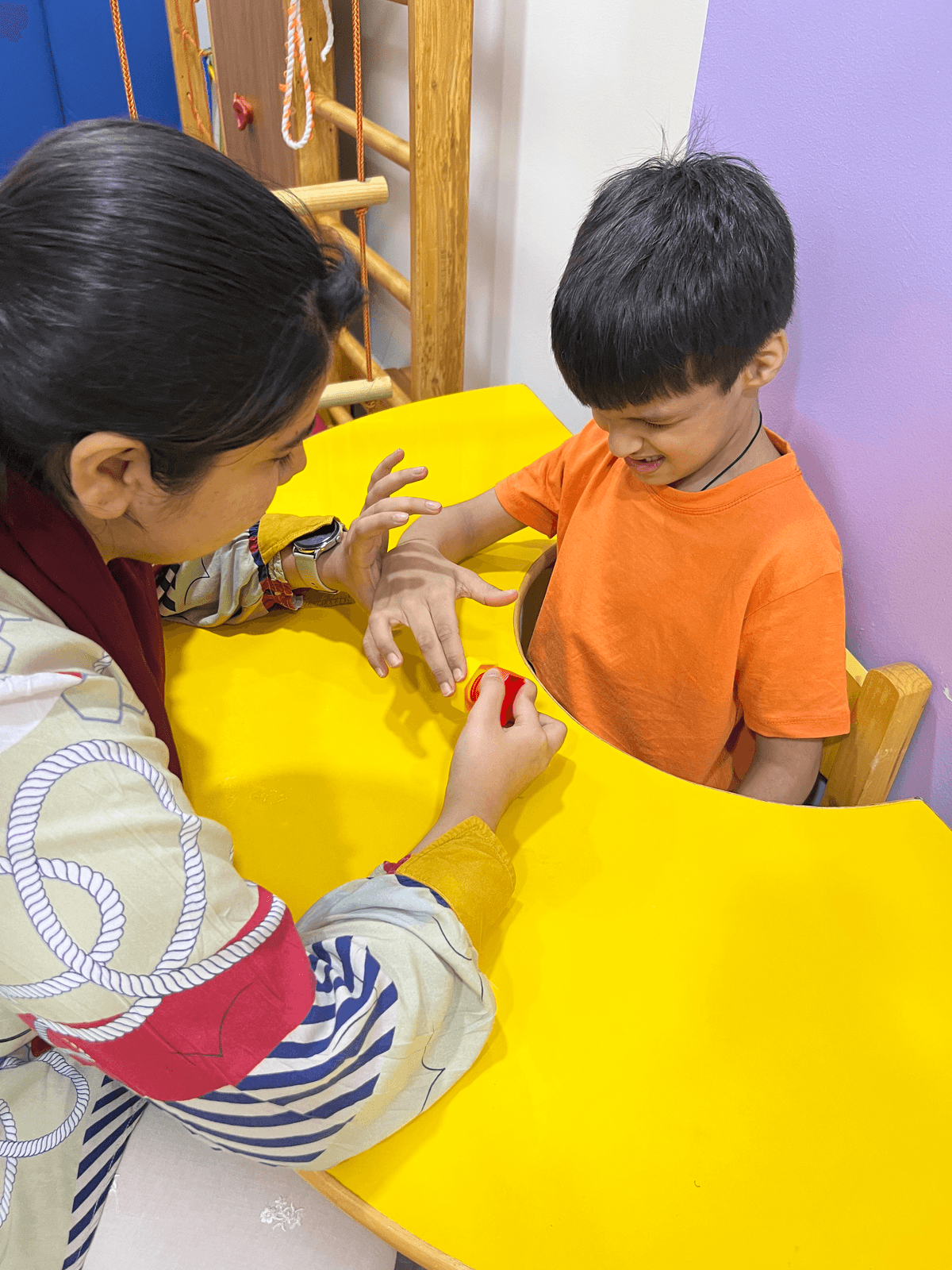 Therapist sitting with child playing drum