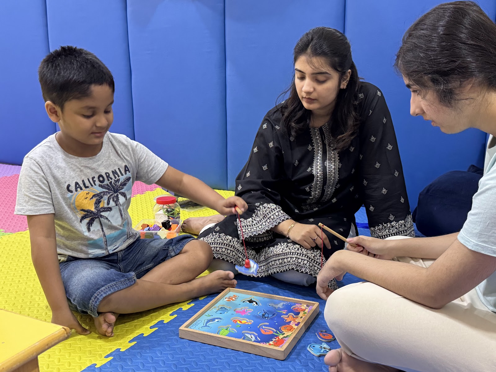 Child engaging in interactive puzzle activity with therapists