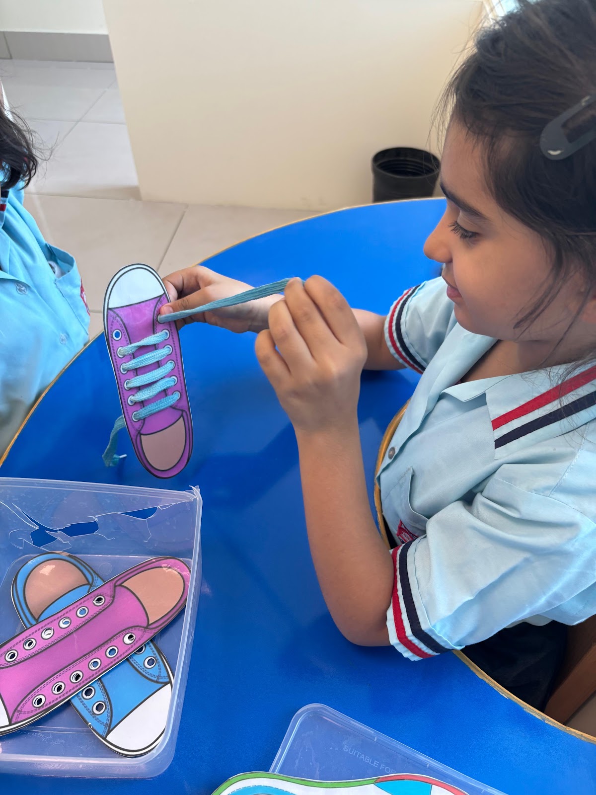 Student practicing fine motor shoe lacing activity