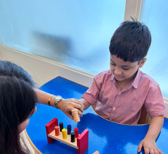 Therapist guiding child in fine motor peg activity