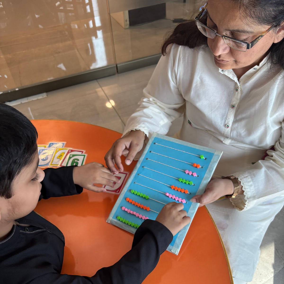 Specialist guiding learner through hands-on counting abacus and activity cards at learning table