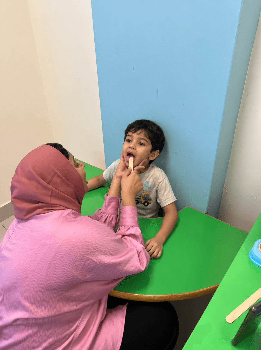 Speech therapist working with boy in mirror