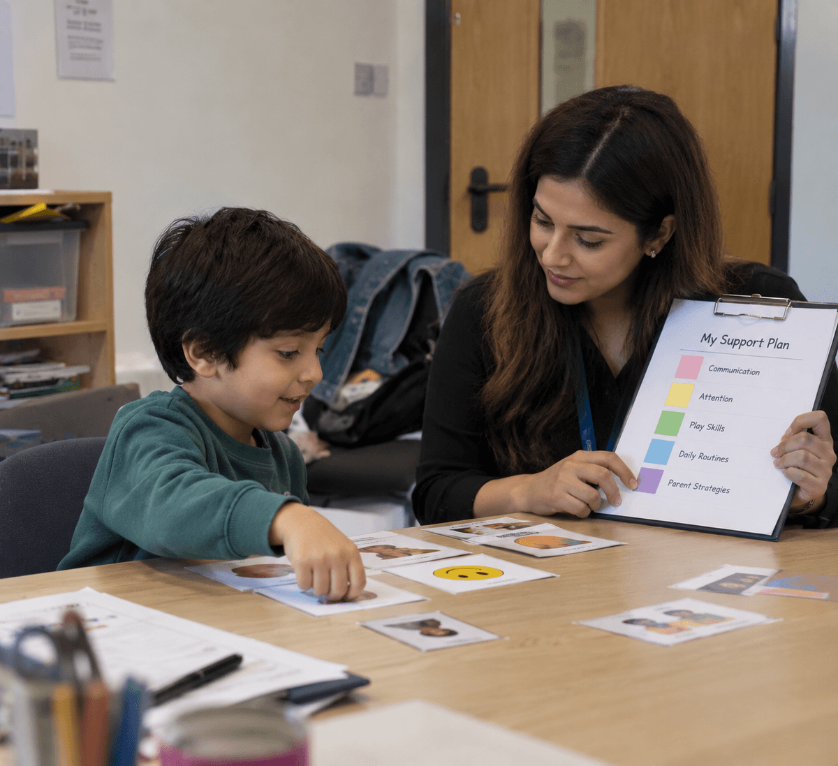Pakistani clinician reviewing individualized Support Plan and assessment goals with child